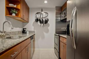 a kitchen with a sink and a stainless steel refrigerator at Urban Gallery Loft - King Bed - Larimer Square in Denver