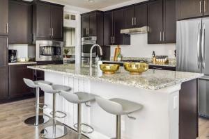 a kitchen with dark brown cabinets and a counter with stools at Modern Elegance - Pool Table - Walkable Area in Aurora