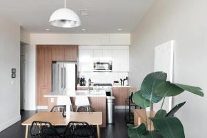 a kitchen with white cabinets and a table and chairs at New Spacious Modern Loft - Center of LoHi in Denver