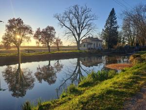 a river with a house in the background with the sun setting at Halte à Ecluse d'Hôte in Calonges +11 photos