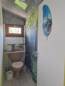 a bathroom with a toilet and a painting on the wall at Halte à Ecluse d'Hôte in Calonges