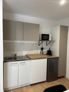 a kitchen with white cabinets and a sink and a microwave at La Cigalière 2 charmant T2 avec terrasse dans villa in Solliès-Ville