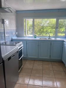 a kitchen with blue cabinets and a sink at Cheerful cottage 3-bedroom in Drehidnaraga Bridge