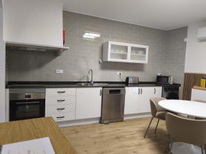 a kitchen with white cabinets and a sink and a table at Flor de Charme in Campo Maior +10 photos