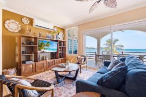 a living room with a blue couch and a tv at Beachfront Penthouse with Panoramic Ocean Views in Playa Flamingo
