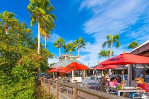 a group of people sitting at tables with umbrellas at Dolphin & Manatee Cove Condo: Beach Access + More! in Gulf City
