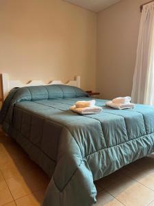 a bedroom with a blue bed with towels on it at Complejo Punto Medio in Santa Rosa
