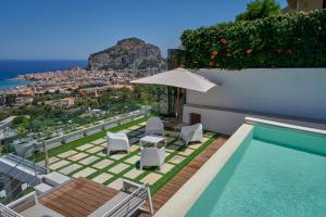a villa with a swimming pool with chairs and an umbrella at Villa AmOr in Cefalù