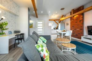 a living room with a gray couch and a kitchen at Apartamenty Centrum - Moonlight in Opole
