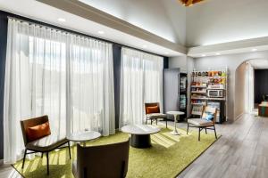 a waiting room with chairs and tables and windows at Spark By Hilton Staunton in Staunton