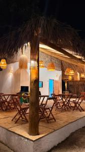 a group of tables and chairs under a straw umbrella at Bossa Atins in Atins