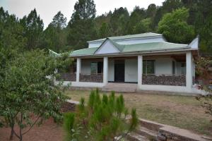 a white house with a green roof at Brookside Pines in Murree