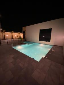 a swimming pool at night with a tv on the wall at فلو بارك in Unayzah