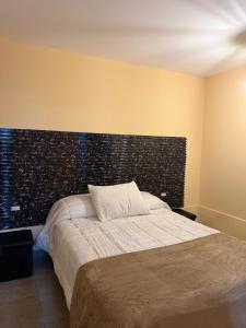 a bedroom with a large bed with a brick wall at Loft Don Bosco in San Luis