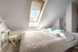 a bedroom with a white bed with a window and a chair at Apartamenty Centrum - Moonlight in Opole