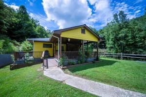 a yellow house with a porch in a yard at Slay The Dragon Dragon's Lair Cabin in Robbinsville, North Carolina w Creek in Robbinsville