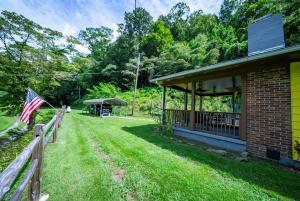 a house with a fence and an american flag at Slay The Dragon Dragon's Lair Cabin in Robbinsville, North Carolina w Creek in Robbinsville