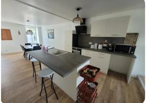a kitchen with a counter and a kitchen island with stools at Le Petit Logis in Beaurepaire