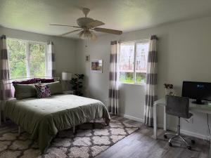 a bedroom with a bed and a desk and windows at Hale Kululoa in Hilo