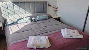 a bedroom with a bed with two towels on it at Cabañas Altos del Sauce in Villa General Belgrano