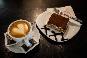 a plate with a piece of cake and a cup of coffee at Hotel XXL in Ferizaj +7 photos