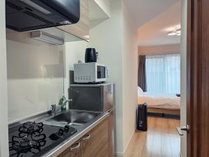 a small kitchen with a sink and a microwave at NUPRIME morishita in Tokyo