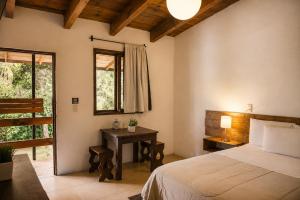 a bedroom with a bed and a table and a window at Meson de Valle Hotel in Valle de Bravo