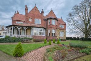 a large red brick house with a garden in front of it at Cober Hill in Scarborough