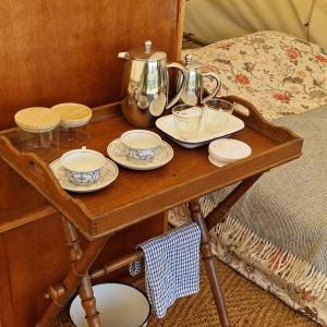 a wooden table with a tea kettle and dishes on it at Eco glamping tent 'Basilikus' in Laakdal +7 photos