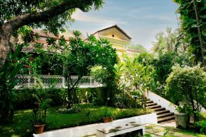 a garden with a bench in front of a house at Serendipity House Goa in Nerul