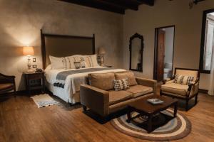 ein Schlafzimmer mit einem Bett, einer Couch und einem Stuhl in der Unterkunft Los Pasos Boutique Hotel & Spa in Antigua Guatemala