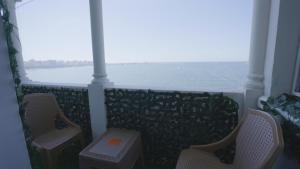 a balcony with chairs and a view of the water at New Welcome House Hotel in Alexandria