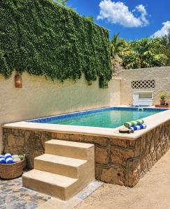 a swimming pool with a stone retaining wall and stairs at Paseo Kuka by ÓOL Hotels in Holbox Island