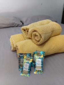 a bed with a towel and two packets of soap at Aero Hospedagem Londrina in Londrina