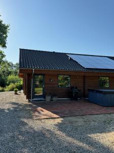 a house with solar panels on top of it at Fredfyldt skovbolig med udespa in Rødding