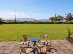 a patio with a table and chairs and a field at The Boathouse in Kilkee