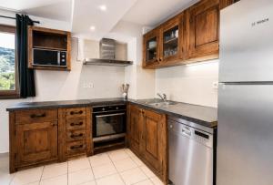 a kitchen with wooden cabinets and a stainless steel refrigerator at Résidence Geffriand - Triplex pour 10 personnes proche des pistes au coeur des 3 Vallées MAE-4944 in Levassaix
