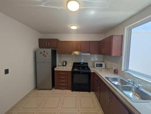 a kitchen with wooden cabinets and a stainless steel refrigerator at Casa Terraza Zacatlan in Zacatlán