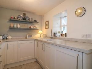 a kitchen with white cabinets and a sink and a window at Sunnyside in Matlock +28 photos