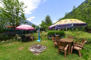 a group of tables and chairs with umbrellas at Hotel O by OYO Manali Meadows Home Stay in Manāli