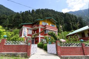 a red brick house with a fence in front of it at Hotel O by OYO Manali Meadows Home Stay in Manāli