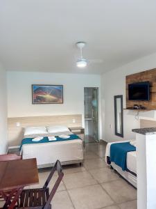 a hotel room with two beds and a television at Di Villa Búzios in Búzios