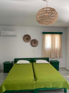 a bedroom with two green beds and a chandelier at Kapares Studios & Apartments in Agia Anna Naxos