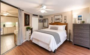 a bedroom with a large white bed and a kitchen at Executive Center Hotel Honolulu in Honolulu