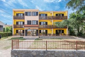 a yellow building with a fence in front of it at Maja Apartments Malinska in Malinska