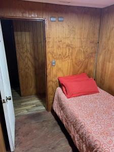 a bedroom with a bed with a red pillow at Hospedaje Ilabaca in Angol