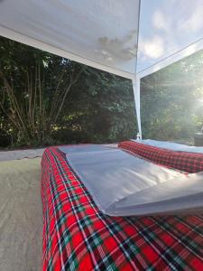 a bed under a white tent with a plaid blanket at Acorn Creek Tented Camp in Nidda