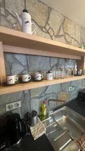 a kitchen counter with a sink and a counter top with cups at Hotel Kukučka Apartament Janka C105 Tatranská Lomnica in Vysoké Tatry
