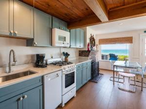 a kitchen with a sink and a stove top oven at Beachfront on Skaket Water Views in Orleans