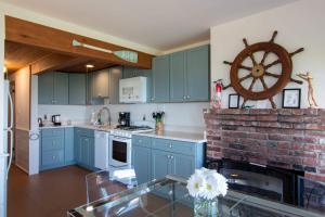 a kitchen with blue cabinets and a brick fireplace at Beachfront on Skaket Water Views in Orleans +26 photos